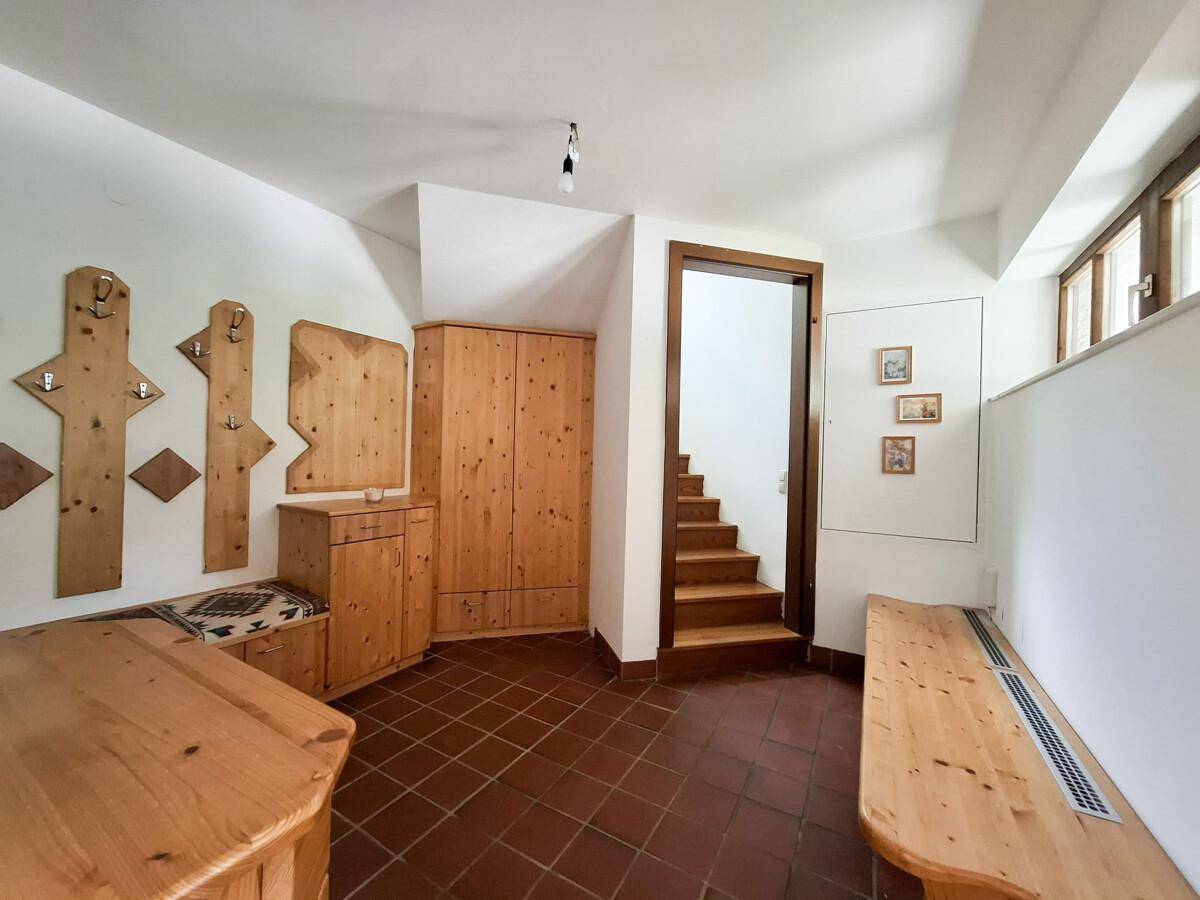 Gemütlicher Eingangsbereich mit Holzmöbeln, Fliesenboden und Treppenzugang.
