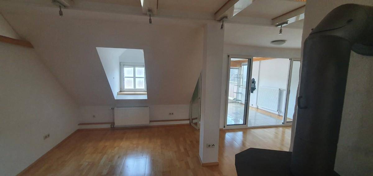 Heller Wohnbereich im Dachgeschoss mit Holzboden, Dachfenster und Heizkörper.