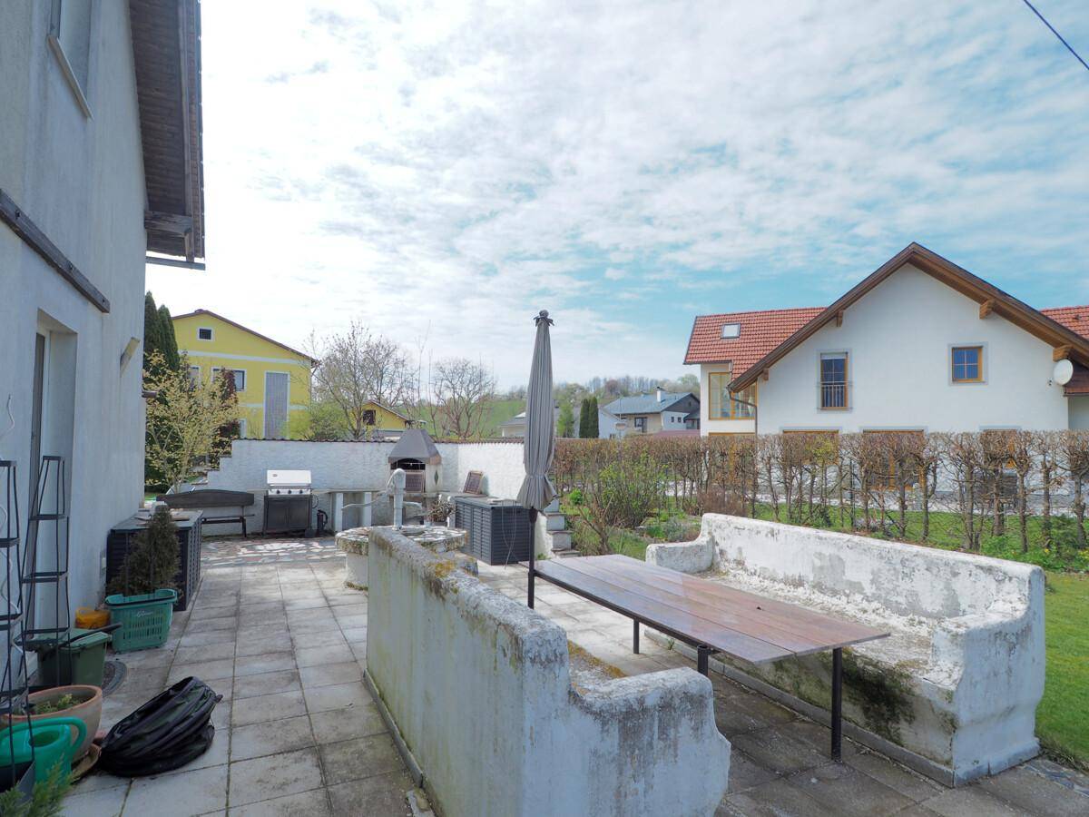Große gepflasterte Terrasse mit fest installierter Sitzbank und Grillbereich für gesellige Abende.