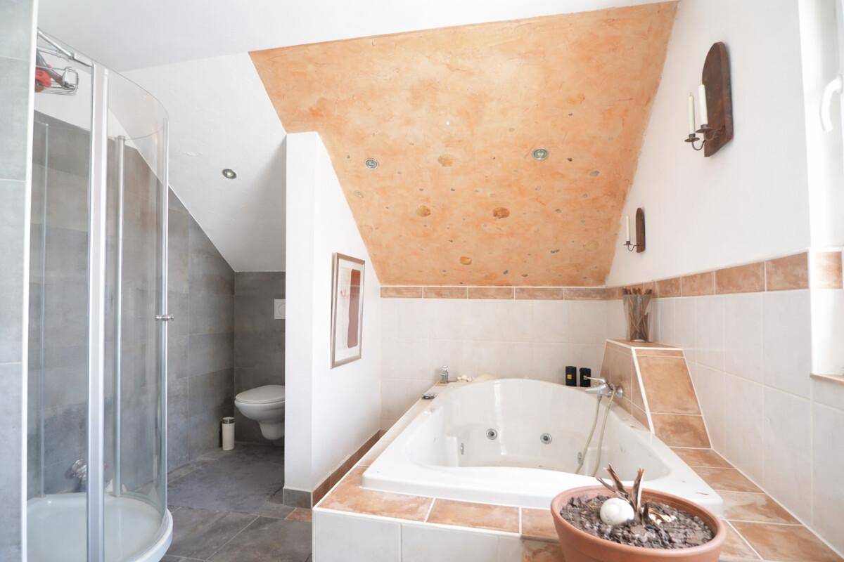 Geräumiges Badezimmer im Dachgeschoss mit Whirlpool, Dusche und Fliesenboden.