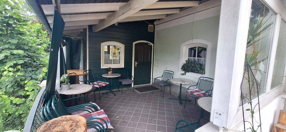 Überdachter Balkon mit Sitzgelegenheiten und Blick ins Grüne, ideal zum Entspannen.