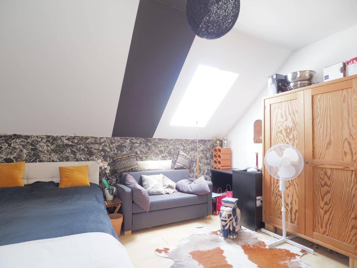 Gemütliches Schlafzimmer im Dachgeschoss mit Dachfenster, Holzboden und dekorativer Wandgestaltung.