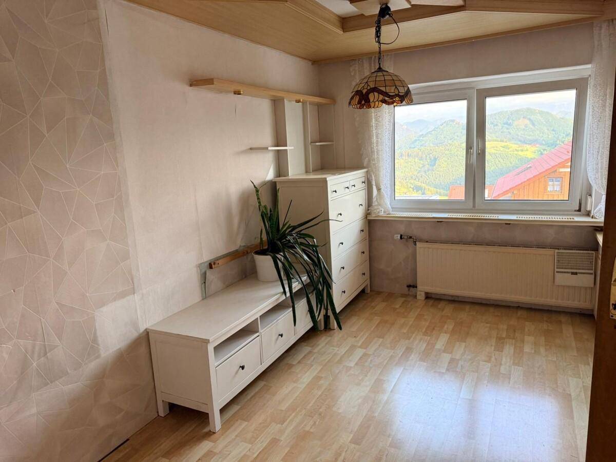 Gemütliches Zimmer mit Laminatboden, Holzdecke und einem Fenster mit Blick auf die Berge.