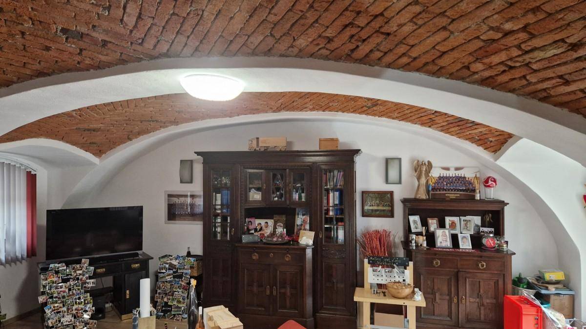 Wohnzimmer mit charakteristischer Ziegelgewölbedecke und antiken Holzschränken, die eine gemütliche Atmosphäre schaffen.