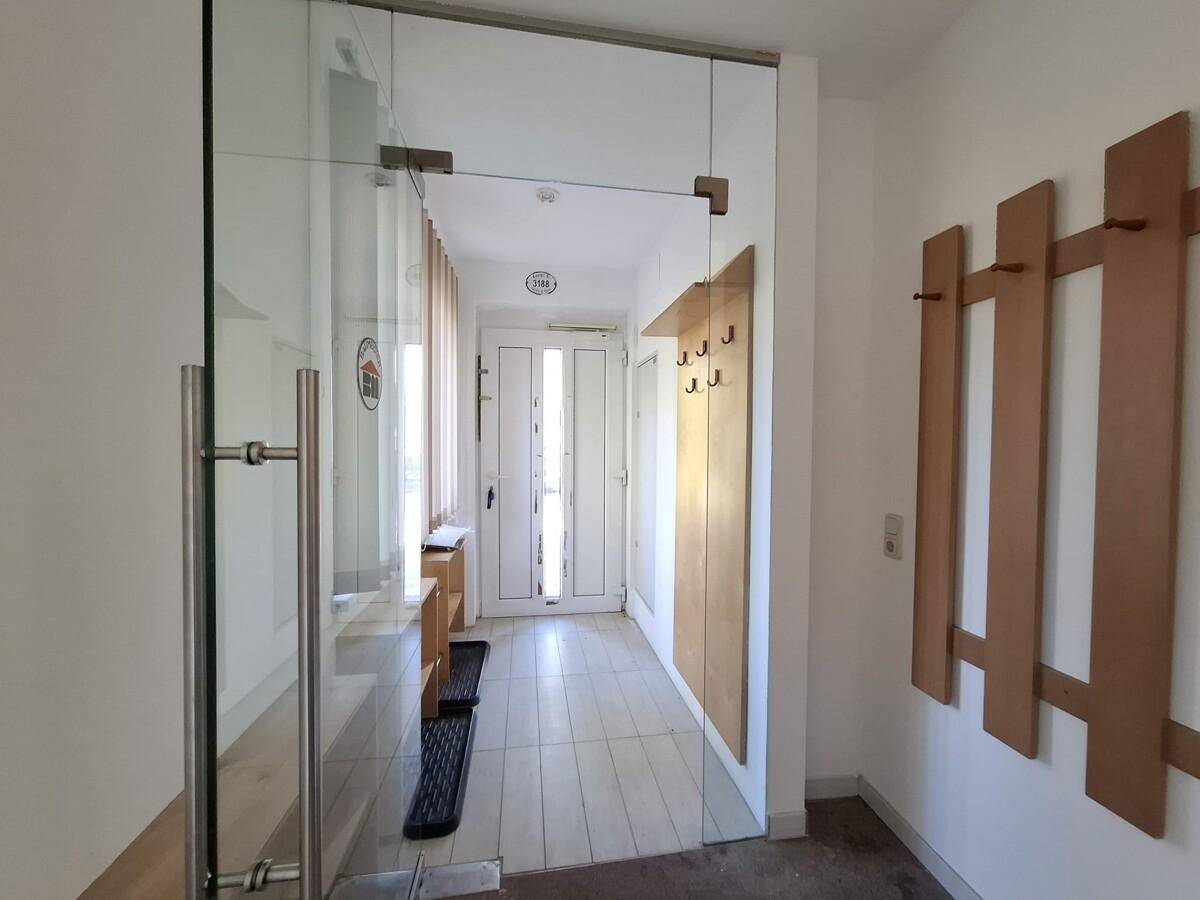Heller Flur mit Glaswand, Garderobe und Zugang zu weiteren Räumen.