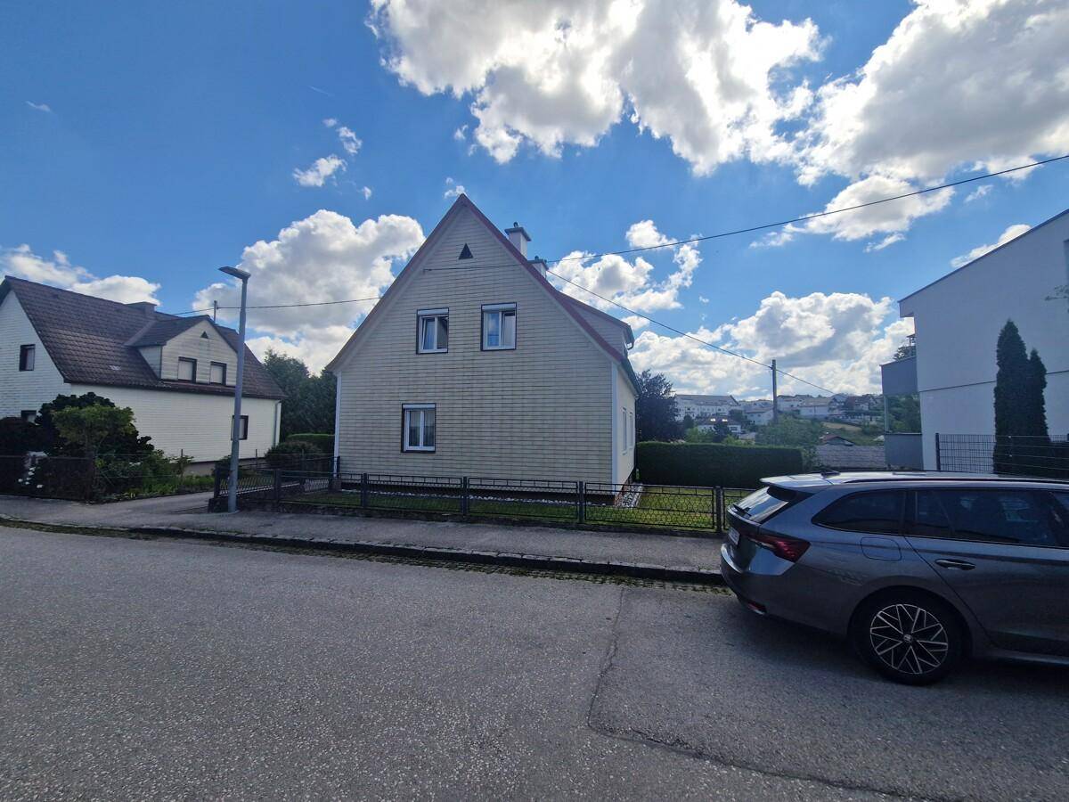 Ansicht der Hausfassade von der Straße aus mit einem kleinen Vorgarten und Zaun.