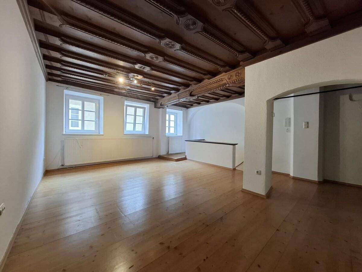 Helles Wohnzimmer mit traditionellen Fenstern, Holzboden und kunstvoll geschnitzter Holzdecke.