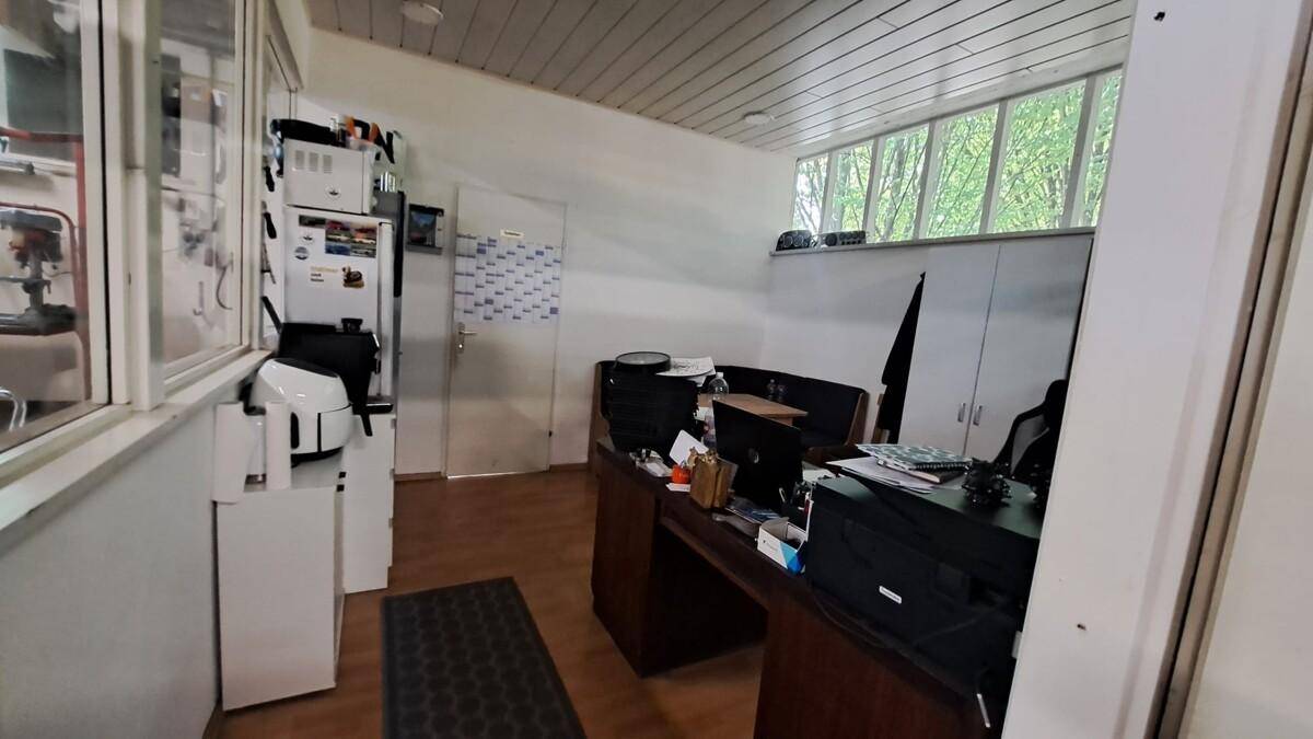 Helles Büro mit Holzdecke, Schreibtisch und großen Fenstern, die viel Tageslicht hereinlassen.