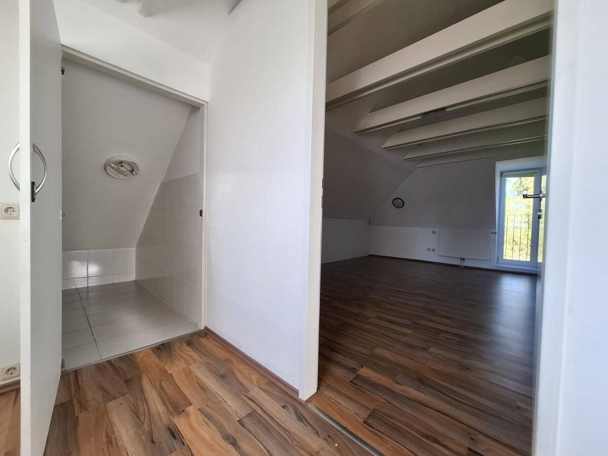 Dachgeschoss mit Abstellraum und offenem Bereich, Holzboden und sichtbaren Deckenbalken.