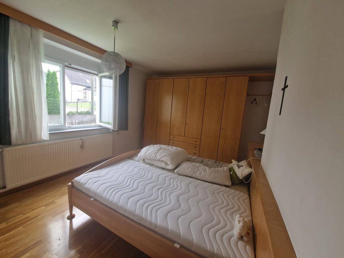 Helles Schlafzimmer mit Holzparkett, großem Fenster und geräumigem Kleiderschrank.