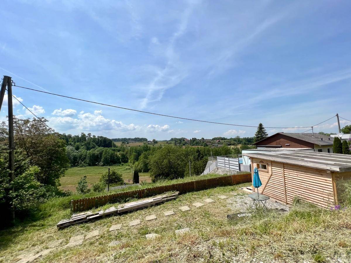 Gartenbereich mit Holzschuppen, kleiner Sitzgelegenheit und weitem Blick ins Grüne.
