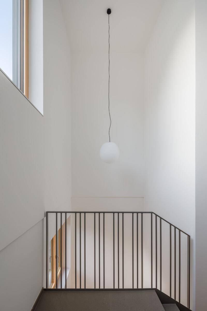 Heller Treppenaufgang mit modernem Geländer und minimalistischer Hängelampe.