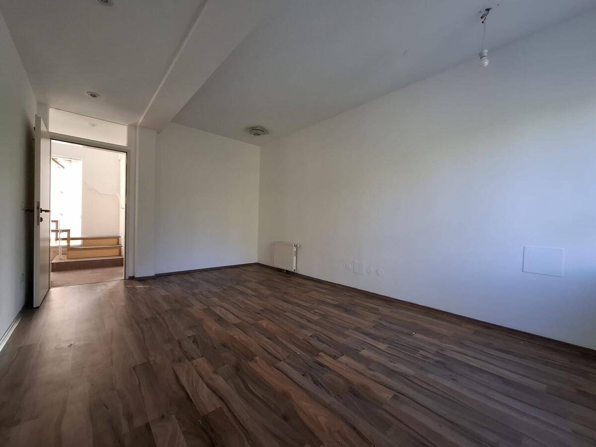 Geräumiger Wohnbereich mit Holzboden und Zugang zur Treppe, hell und offen gestaltet.