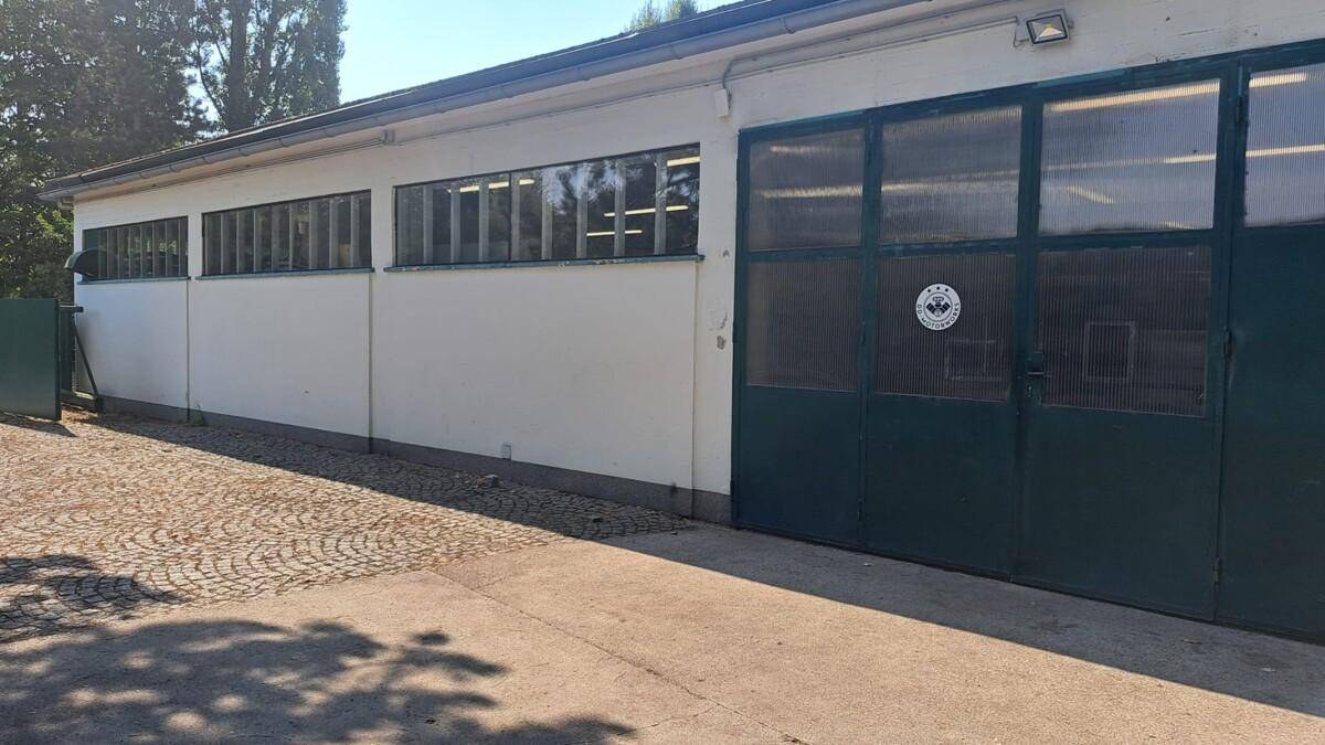 Außenansicht des Werkstattgebäudes mit großen Fenstern und einem breiten Garagentor.