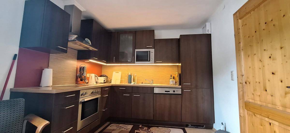 Moderne Küche mit dunklen Holzschränken, integrierten Geräten und indirekter Beleuchtung.