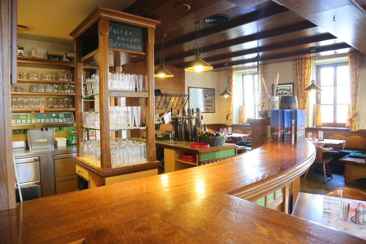Detailansicht der Bar mit Holztheke, Gläserregalen und traditioneller Einrichtung.