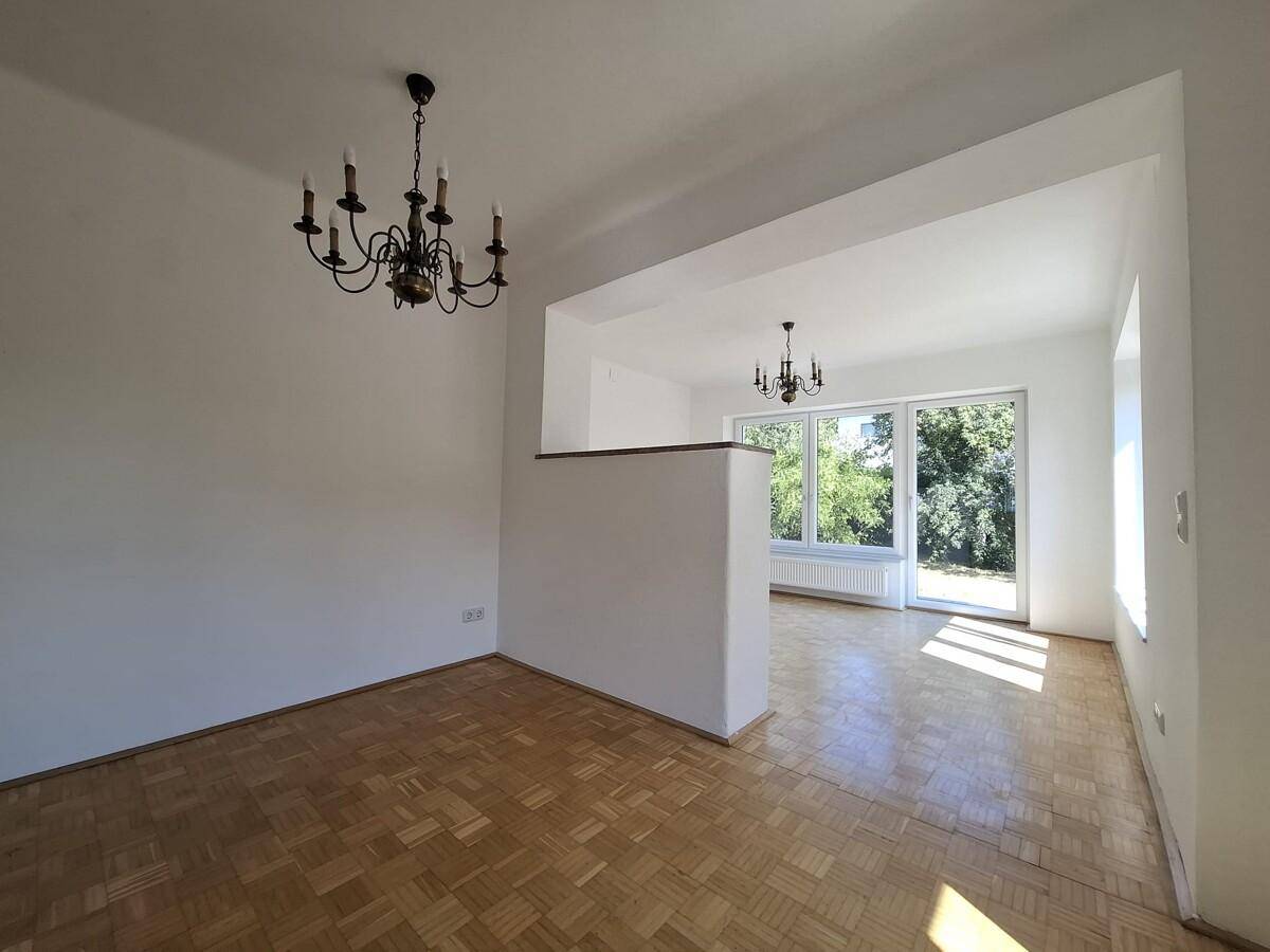 Offener Wohn- und Essbereich mit Parkettboden und viel Tageslicht durch große Fenster.