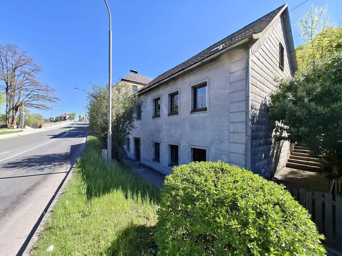 Gesamtansicht des Gebäudes von der Straße aus mit umliegender Vegetation und blauem Himmel.