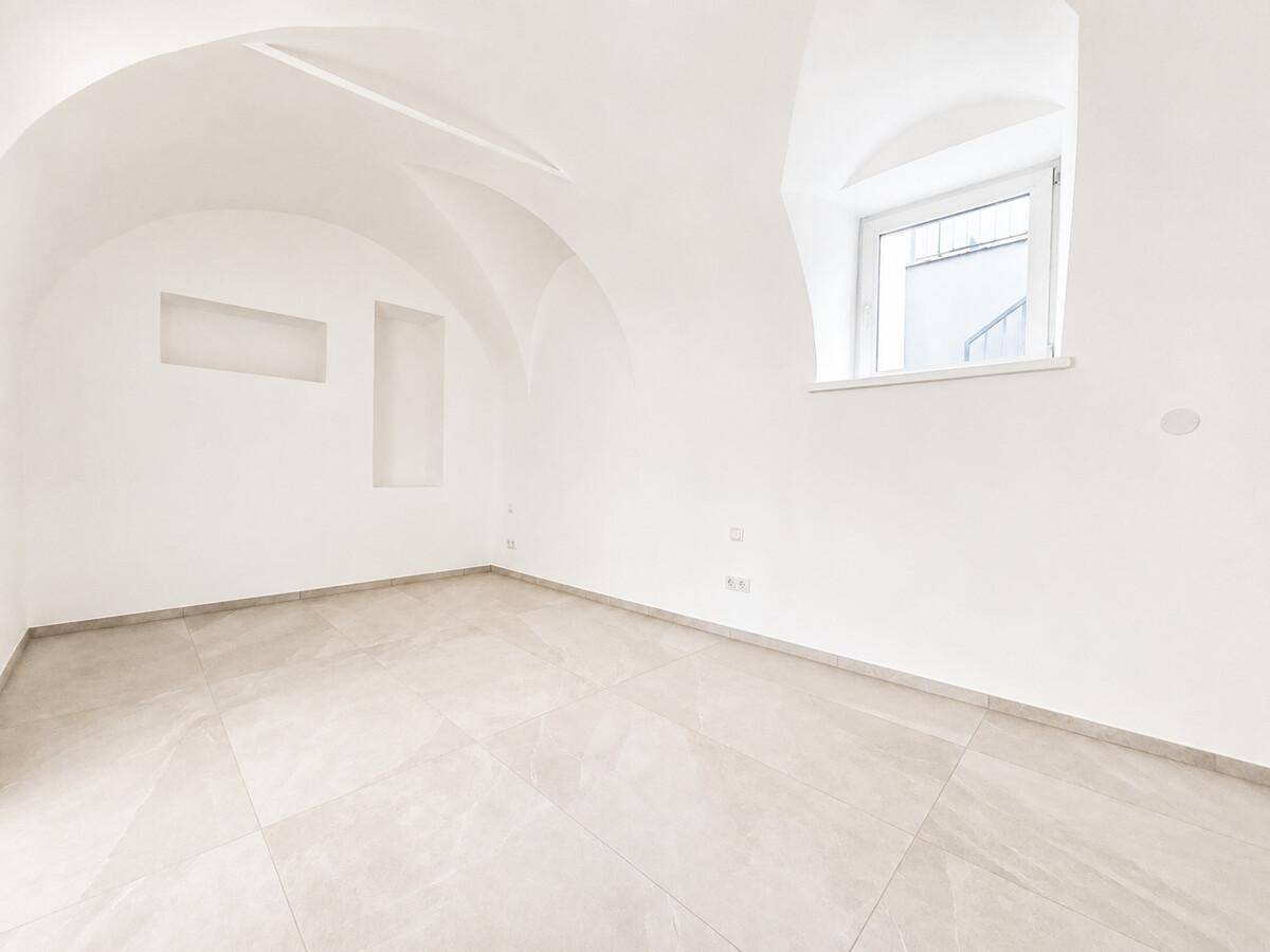 Helles Schlafzimmer mit einzigartiger Gewölbedecke, modernen Fliesen und einem Fenster.