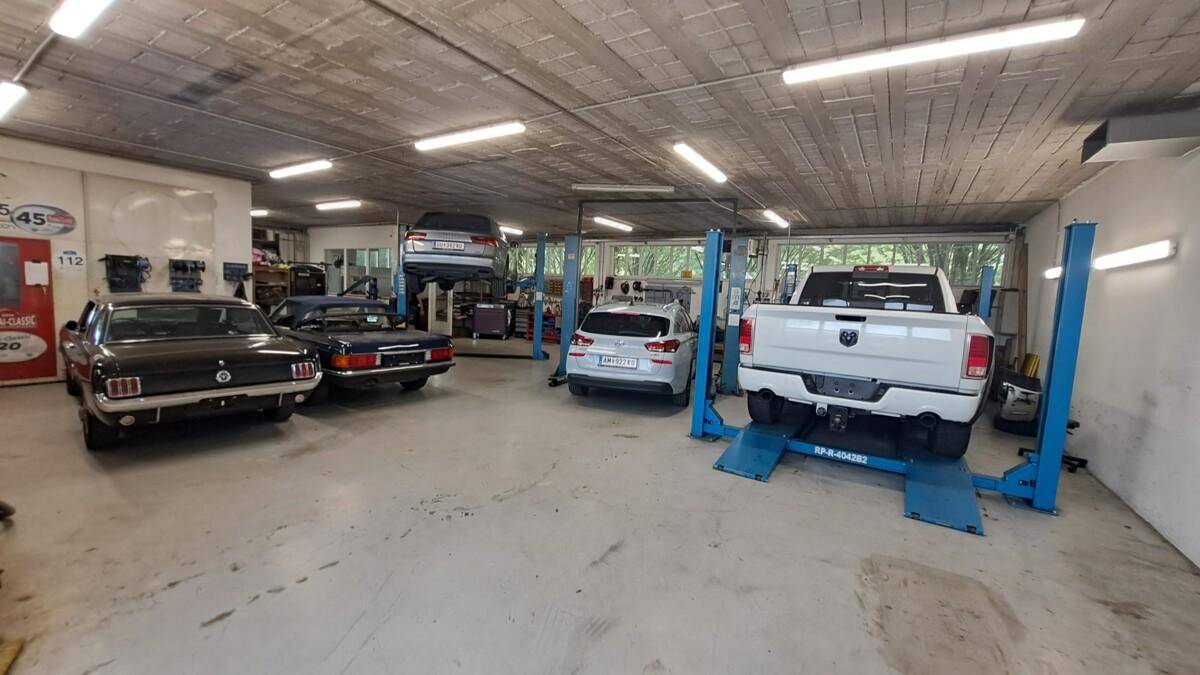 Geräumige Autowerkstatt mit mehreren Hebebühnen, Fahrzeugen und einer robusten Betonbodenfläche.