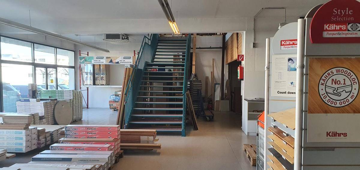 Blick auf eine Treppe in einem Verkaufsraum, umgeben von Auslagen für Bodenbeläge.