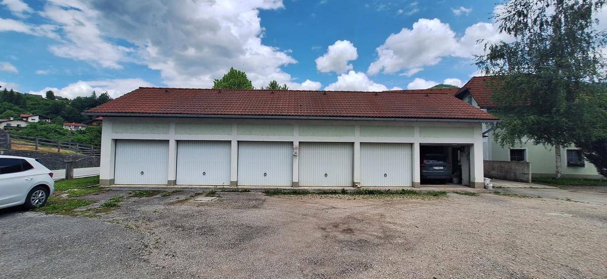 Mehrere Garagen mit weißen Toren und einem roten Ziegeldach, Teil des Anwesens.