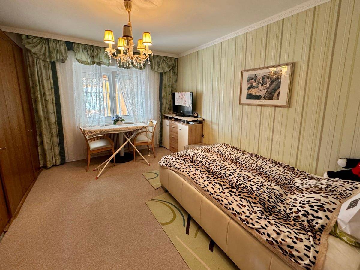 Gemütliches Schlafzimmer mit Teppichboden, Einzelbett und traditioneller Einrichtung.