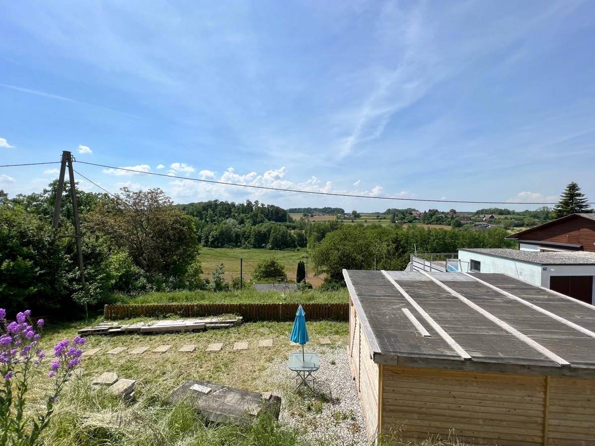 Gartenfläche mit einem Holzschuppen, einer kleinen Sitzgruppe und weitem Landschaftsblick.