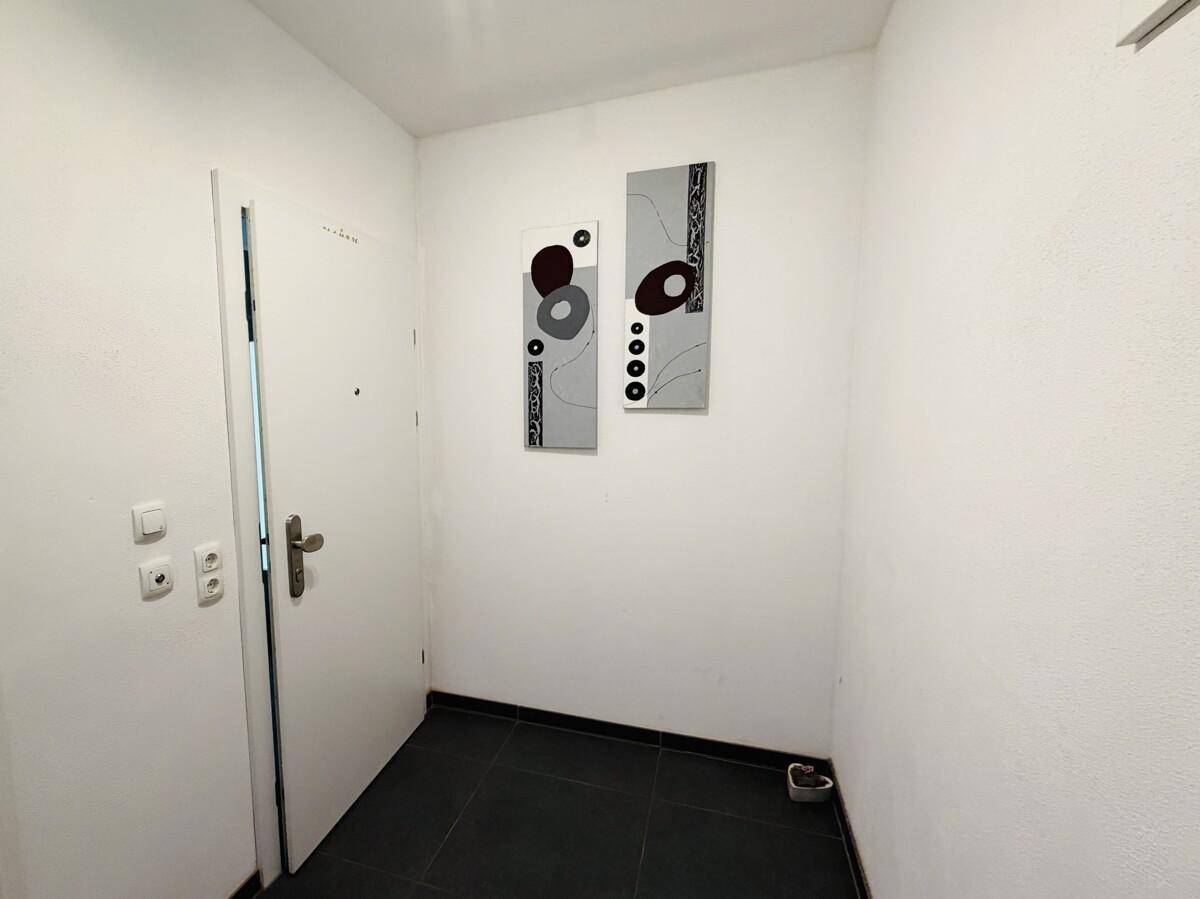Eingangsbereich mit moderner Wanddekoration und dunklen Bodenfliesen.