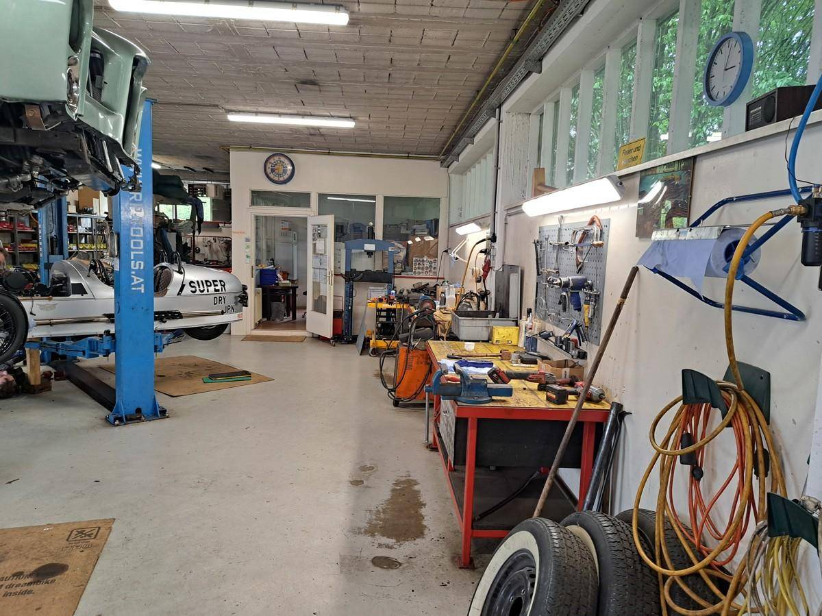 Organisierter Arbeitsbereich in der Werkstatt mit Werkzeugen und einem Fahrzeug auf der Hebebühne für Reparaturen.