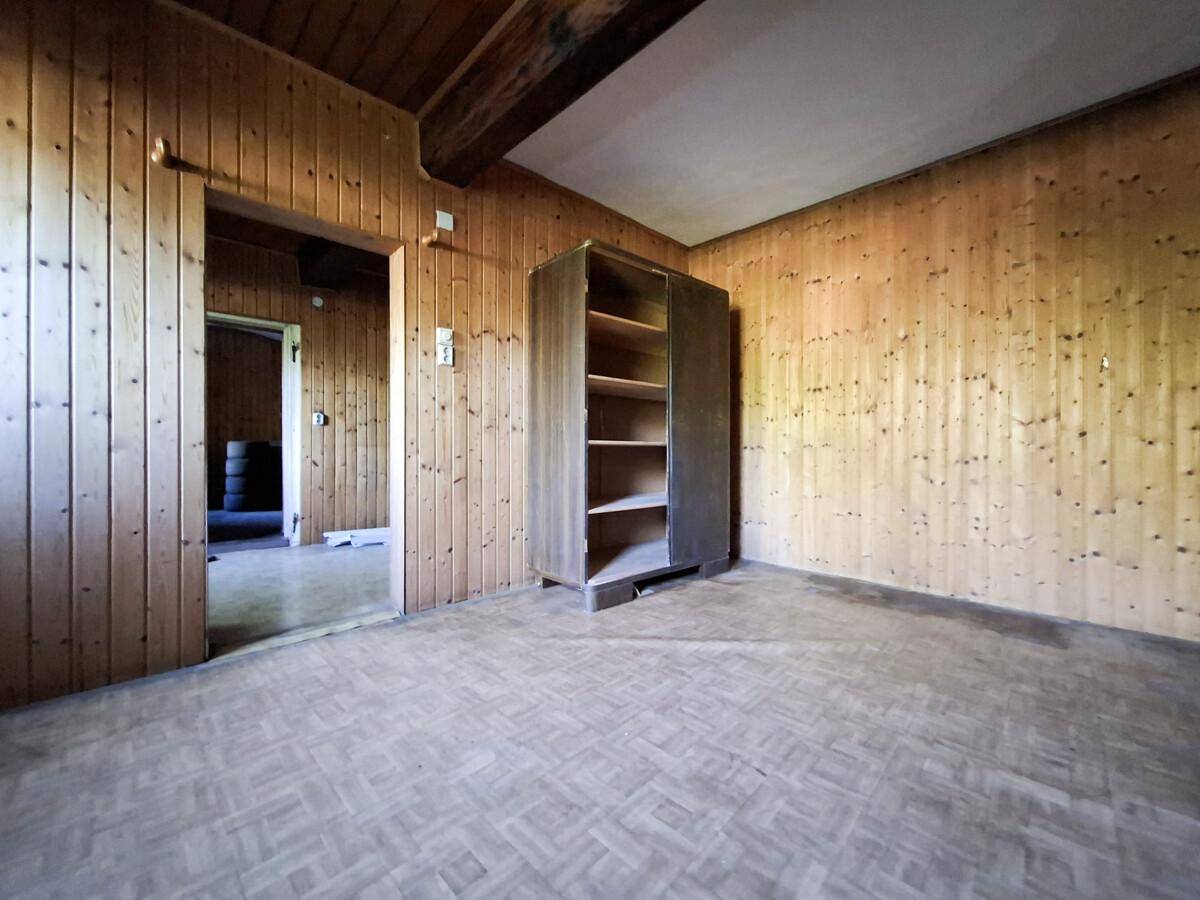 Raum mit Holzvertäfelung an den Wänden, Holzboden und einem Schrank.