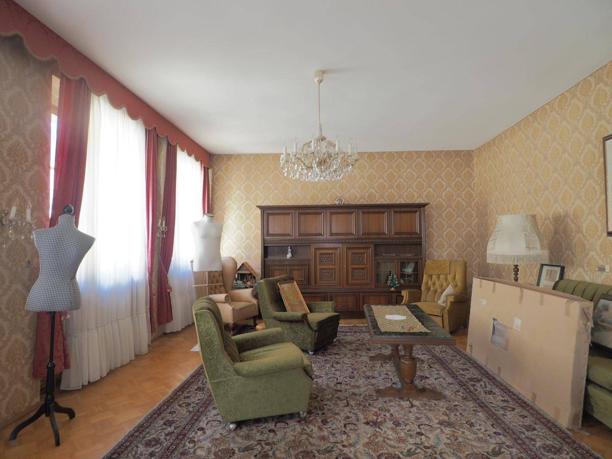 Geräumiges Wohnzimmer im Vintage-Stil mit gemusterter Tapete und Kronleuchter.