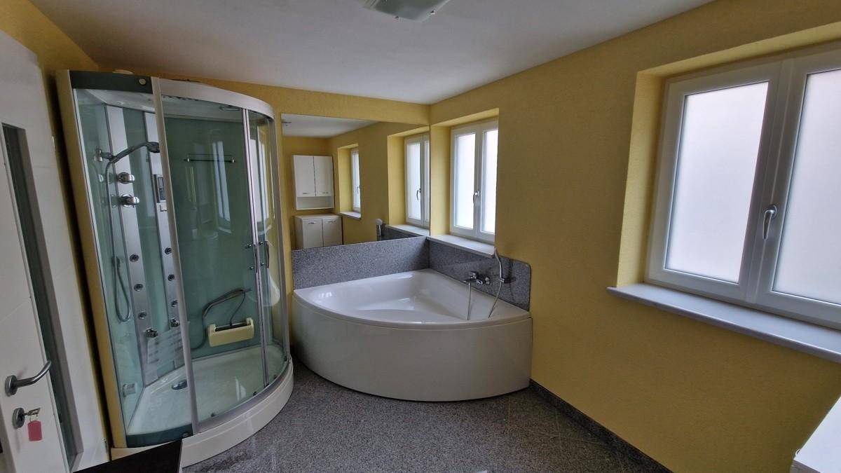 Geräumiges Badezimmer mit Eckbadewanne, Duschkabine und gelben Wänden, das viel Platz bietet.