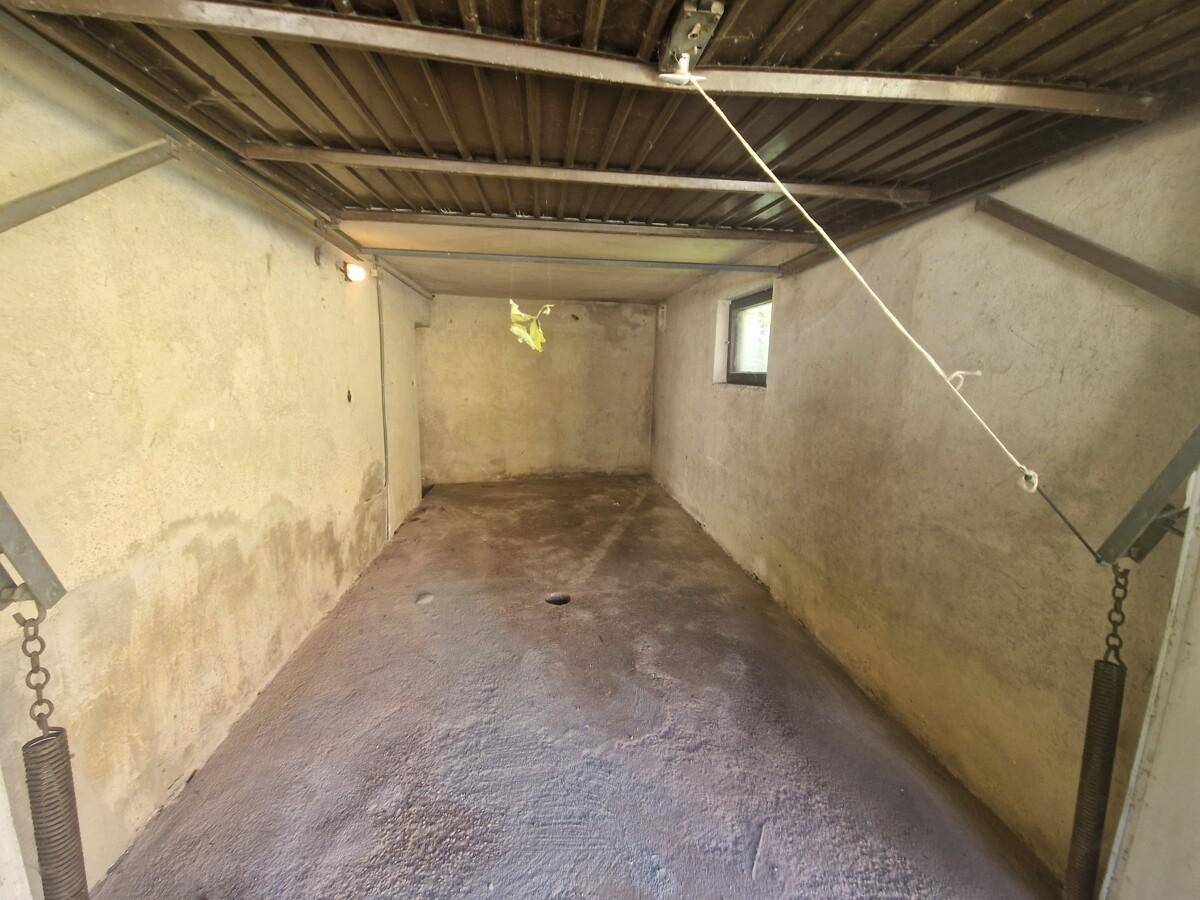 Einfache Garage oder Abstellraum mit Betonboden und unverputzten Wänden.