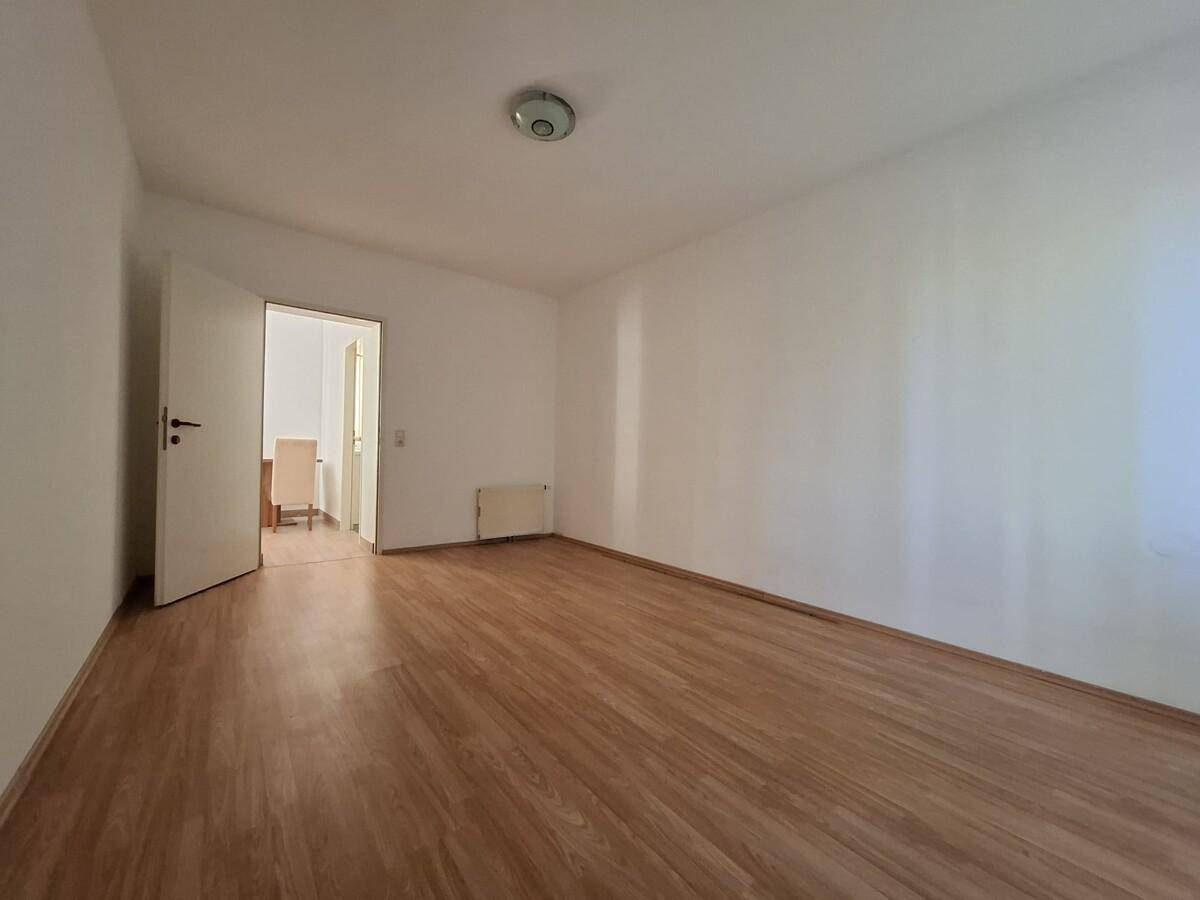 Leeres Schlafzimmer mit Laminatboden und Zugang zu einem weiteren Raum.