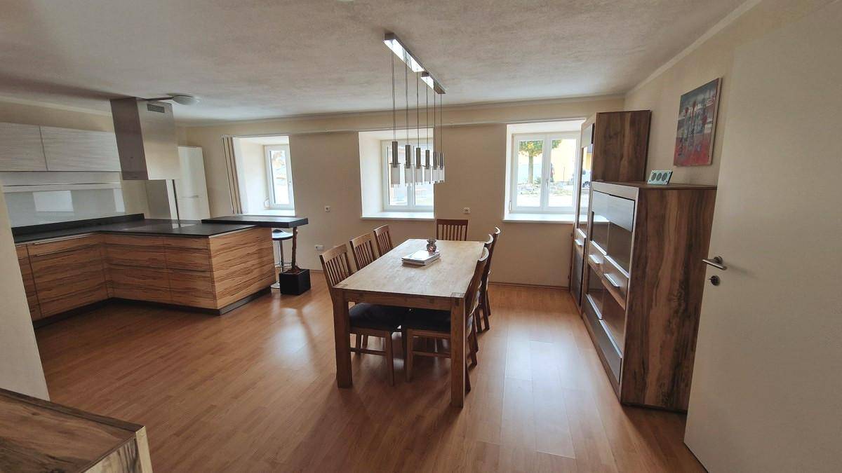Geräumiger offener Wohn- und Essbereich mit Holzboden und moderner Küche, ideal für geselliges Beisammensein.