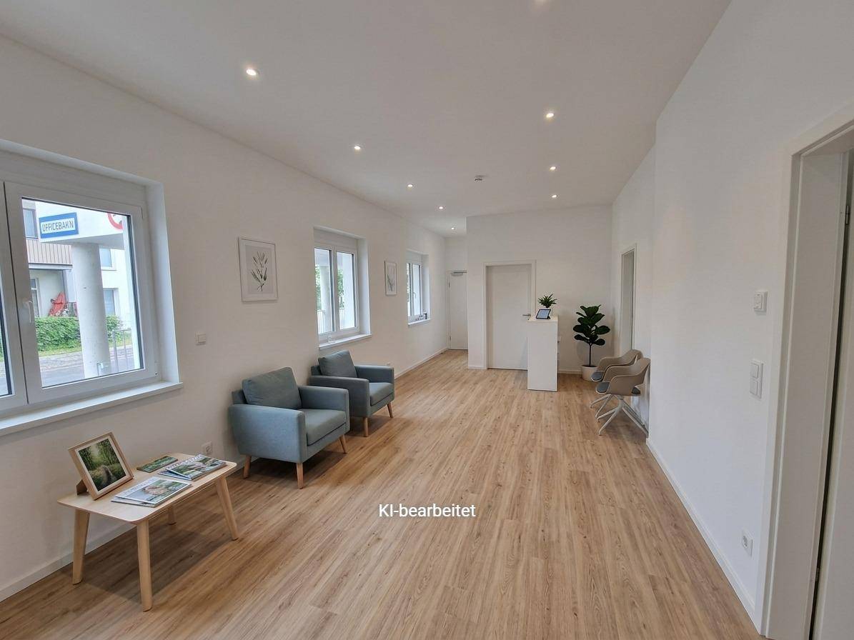Geräumiger Wartebereich mit Holzoptikboden, bequemen Sesseln und viel Tageslicht.