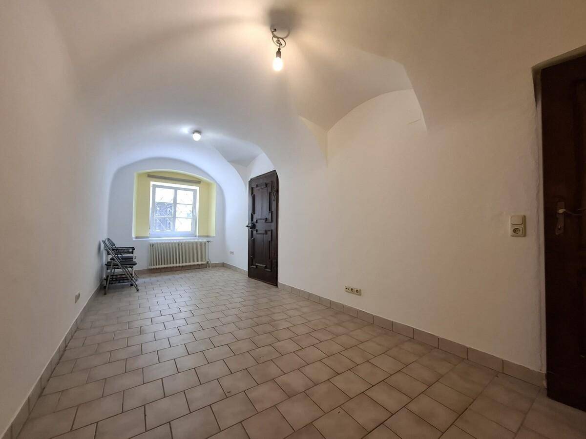Kellerraum mit Gewölbedecke, gefliestem Boden und einem Fenster.