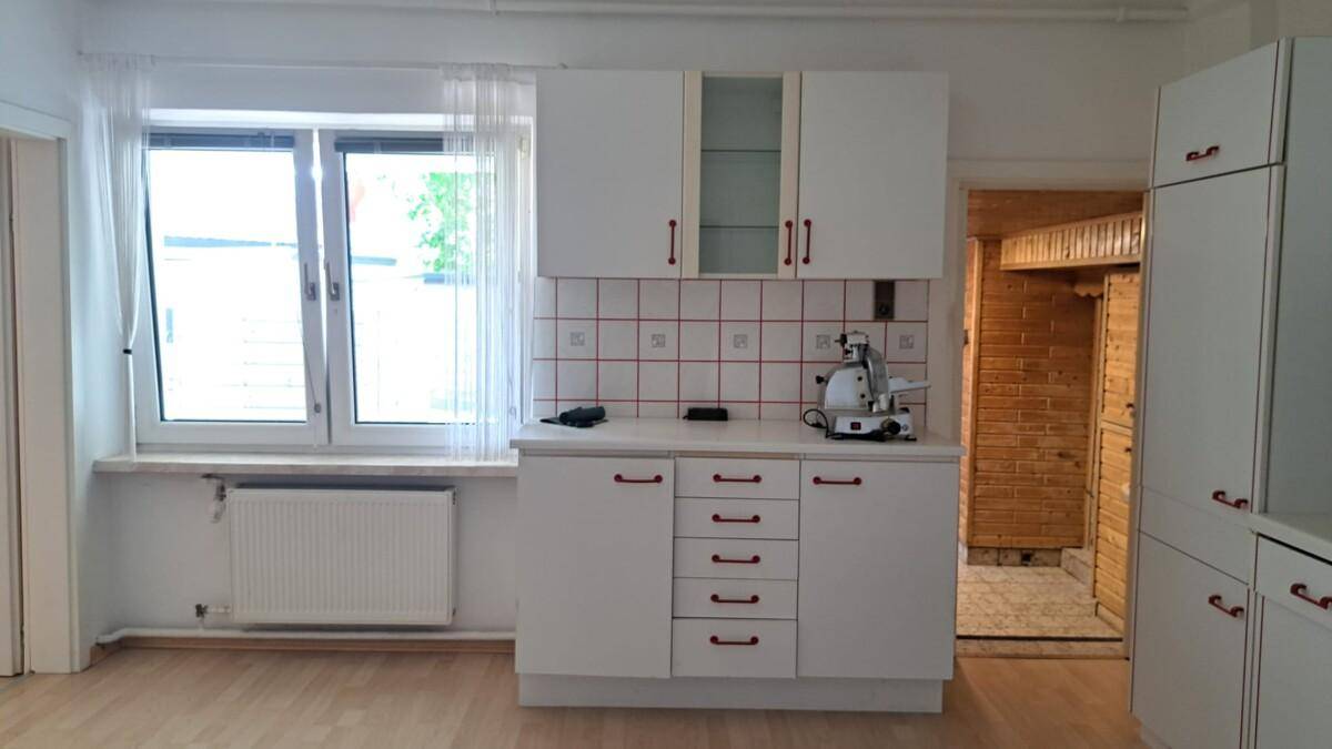 Helle Küche mit weißen Schränken und Fenster, bereit für die Installation von Geräten.