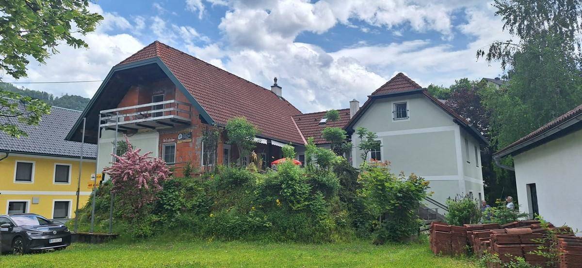 Weitläufige Außenansicht des Hauses mit rotem Ziegeldach und einem gepflegten Rasenbereich.