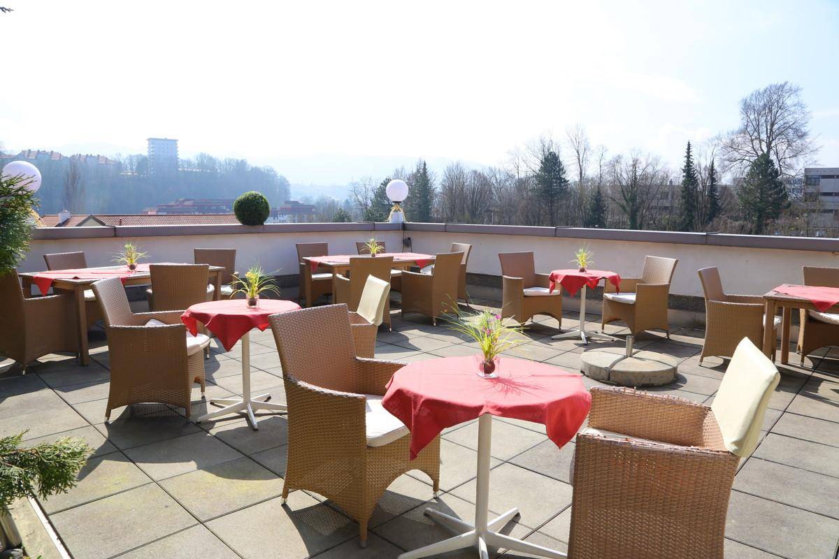 Sonnige Dachterrasse mit Korbmöbeln und weitem Blick über die Umgebung.