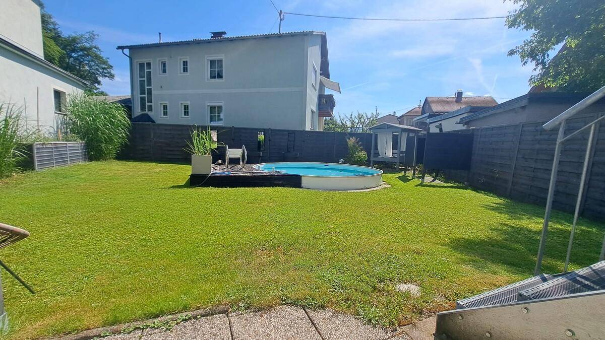 Großer Gartenbereich mit gepflegtem Rasen und einem runden oberirdischen Pool.