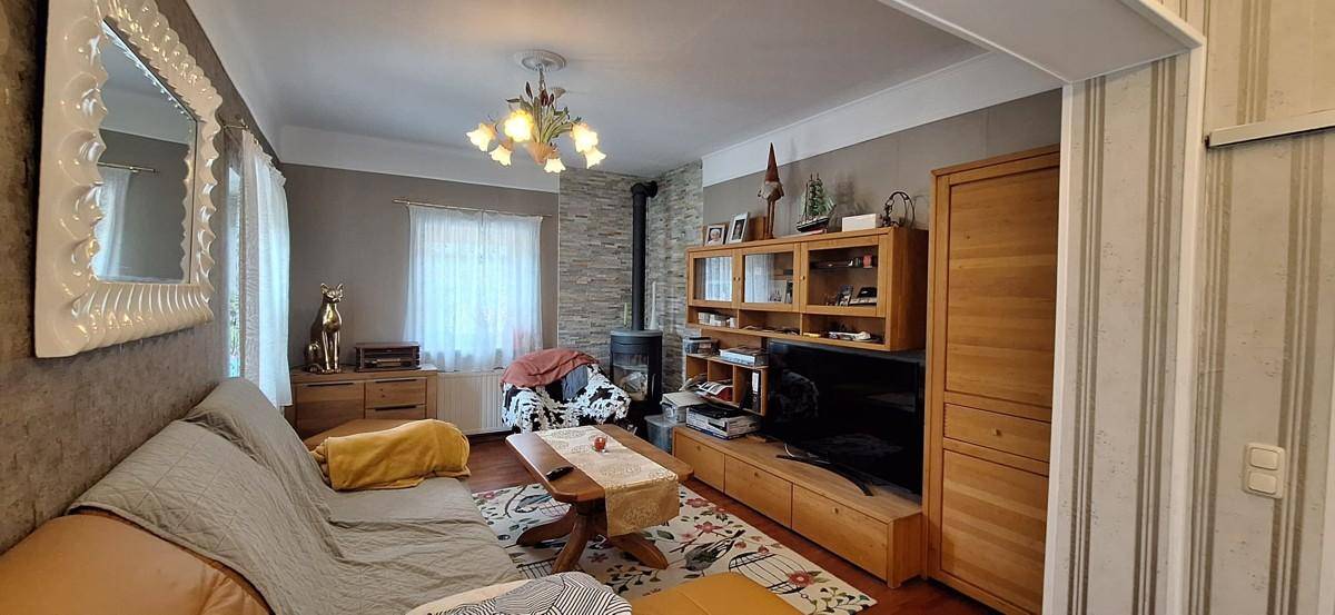 Gemütliches Wohnzimmer mit Holzboden, Kaminofen und traditionellen Holzmöbeln.