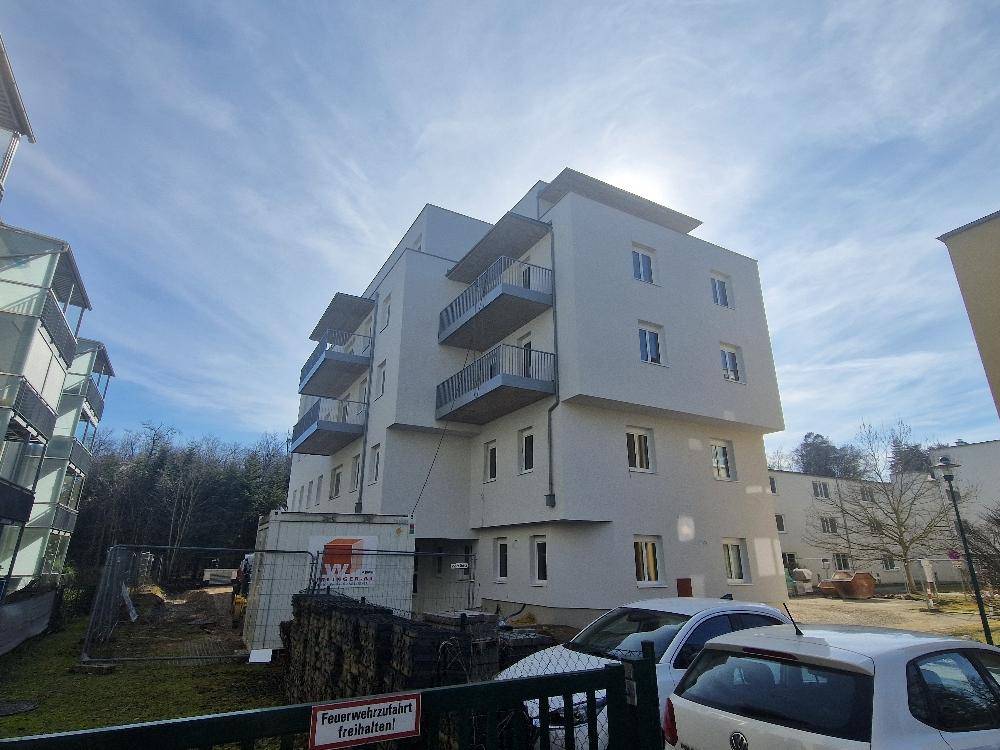 Modernes Wohnhaus mit Balkonen und sonniger Ausrichtung, umgeben von Bäumen.