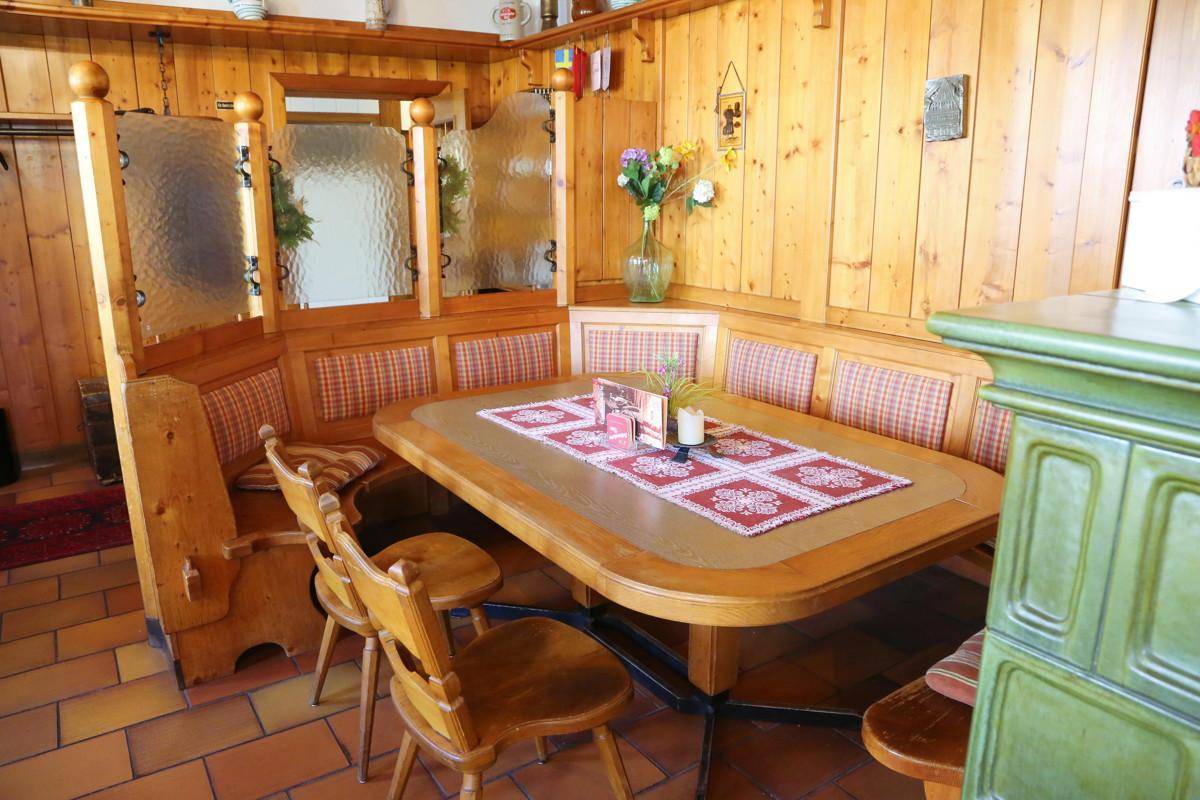 Traditionelle Sitzecke mit Holzbänken, Tisch und karierten Polstern in einem Restaurant.