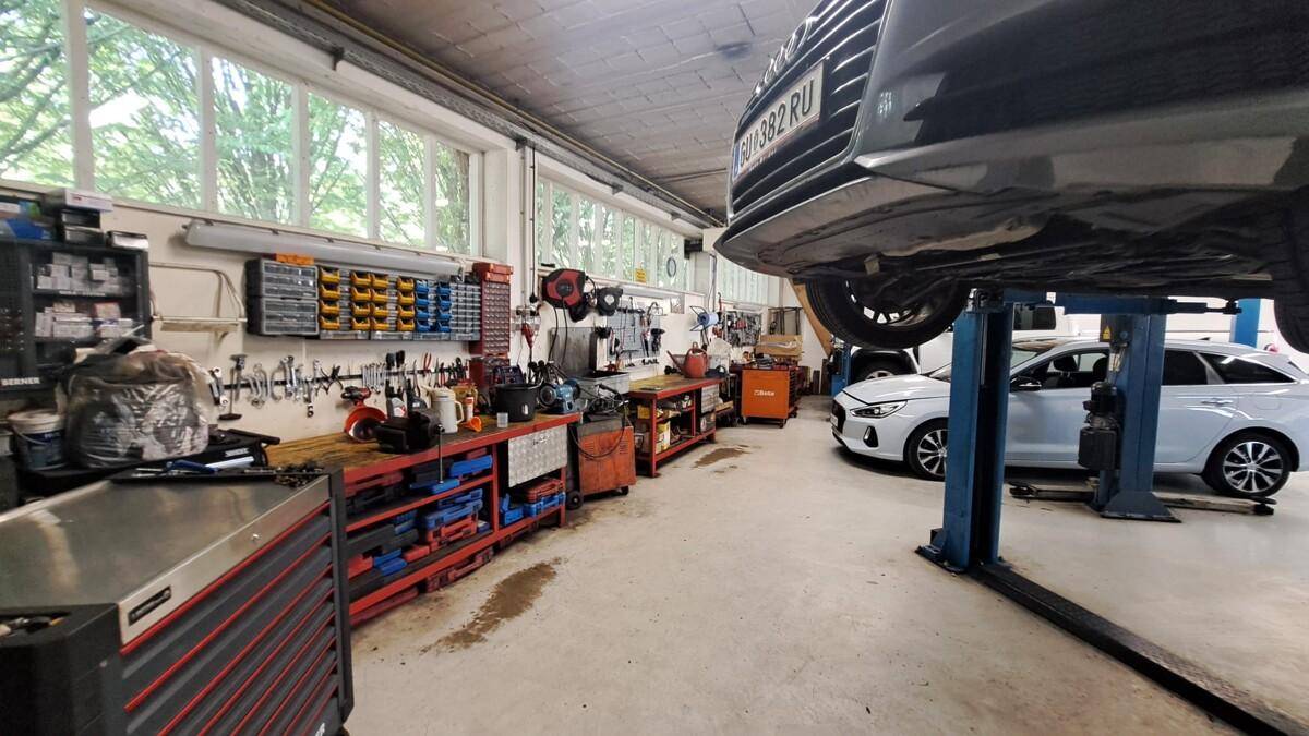 Werkstattbereich mit umfangreicher Werkzeugausstattung, Werkbänken und einem Fahrzeug auf der Hebebühne.