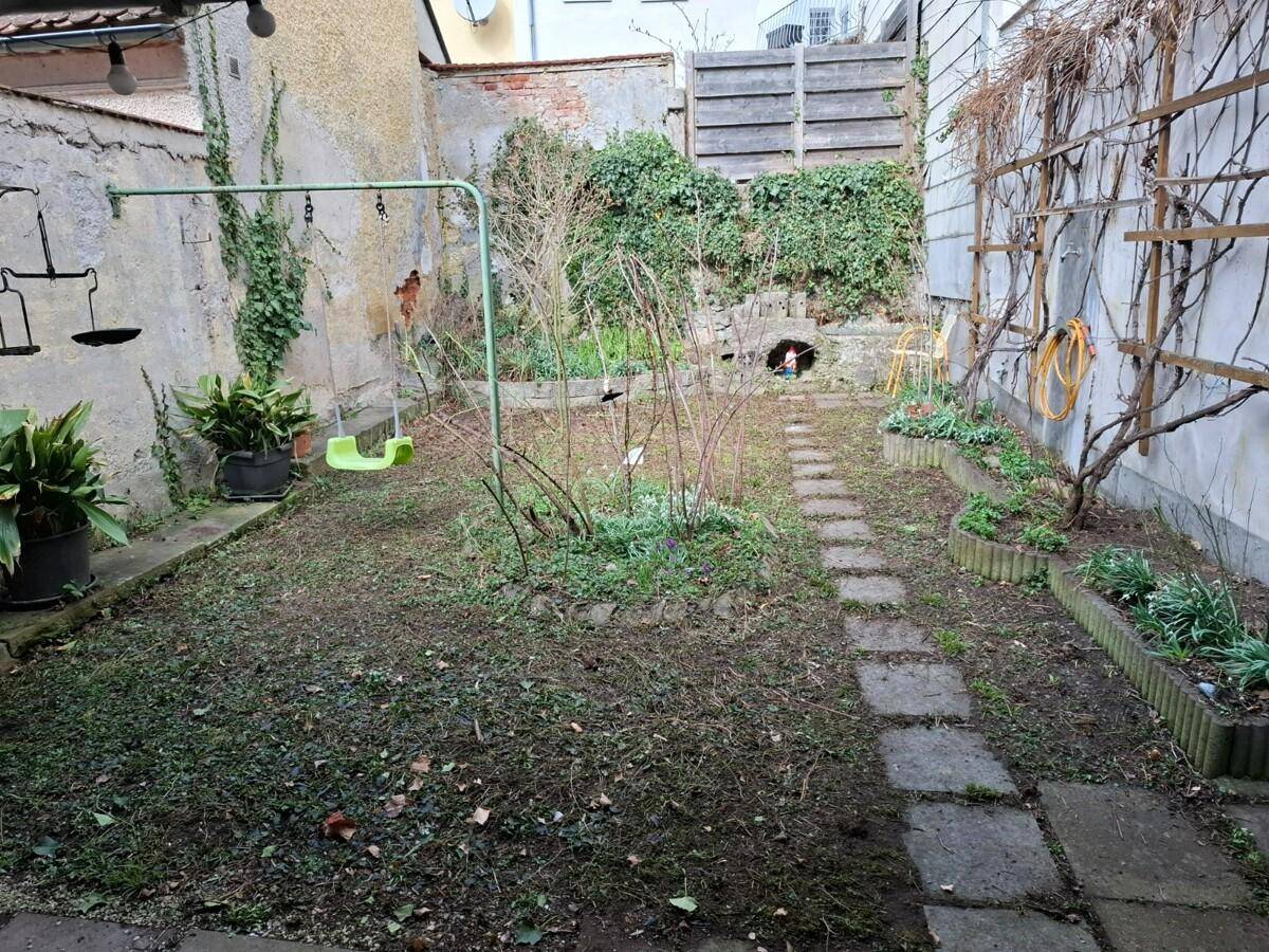 Kleiner Garten mit Rasenfläche, Trittsteinen und Schaukel, ideal für Kinder.