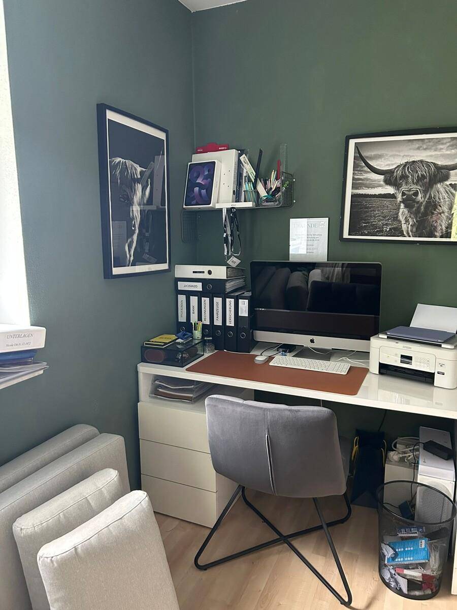 Funktionales Heimbüro mit Schreibtisch, Computer und grünen Wänden für eine angenehme Arbeitsatmosphäre.