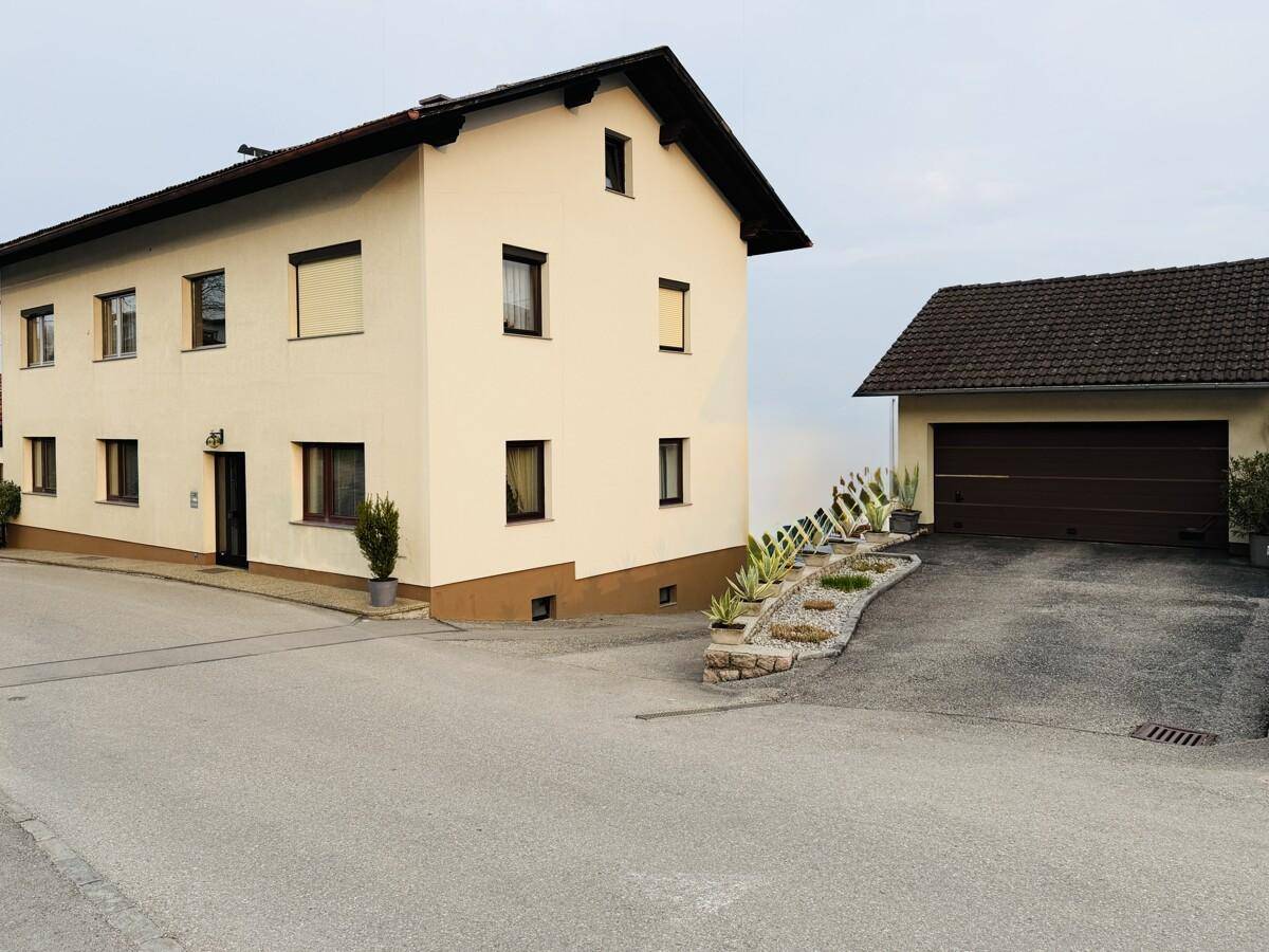 Seitenansicht des Hauses mit Zufahrt zur Doppelgarage und gepflegter Außenanlage.