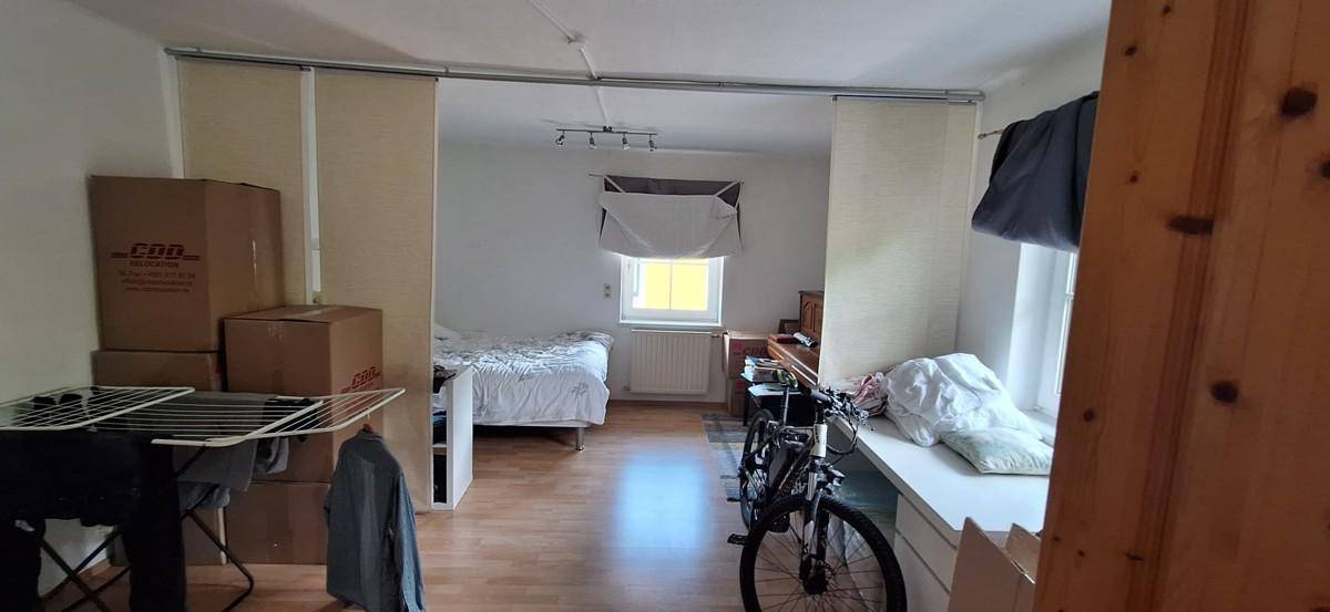 Schlafzimmer mit Holzboden, einem Bett und einem Fahrrad, das den Raum teilt.